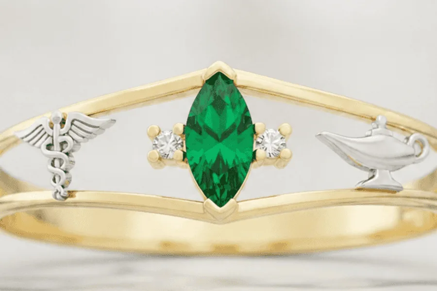 Anel de formatura com pedra verde marquise ladeada pelo caduceu e pela lamparina nas laterais